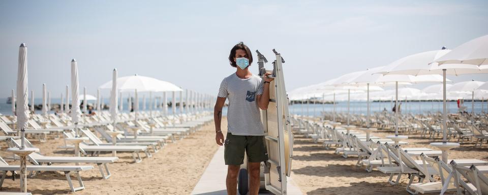 Un plagiste installe des transats pour accueillir les touristes sur une plage privée à Rimini en Italie. [EPA - Max Cavallari - Keystone]