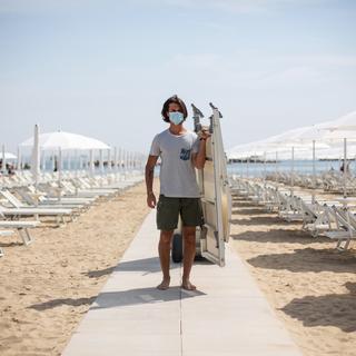 Un plagiste installe des transats pour accueillir les touristes sur une plage privée à Rimini en Italie. [EPA - Max Cavallari - Keystone]