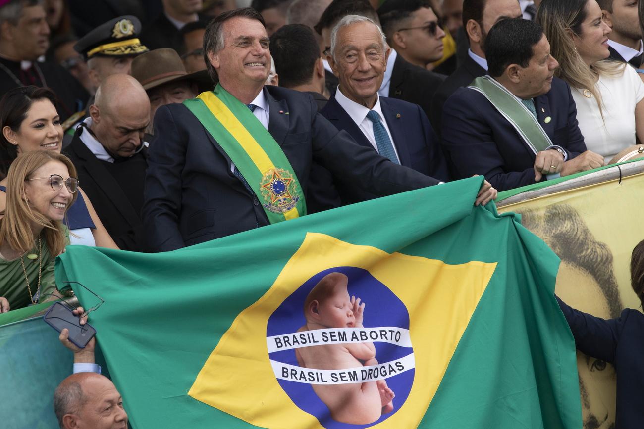 Le président Bolsonaro avec une drapeau contre l'avortement et la légalisation des drogues. [EPA/Keystone - Joedson Alves]