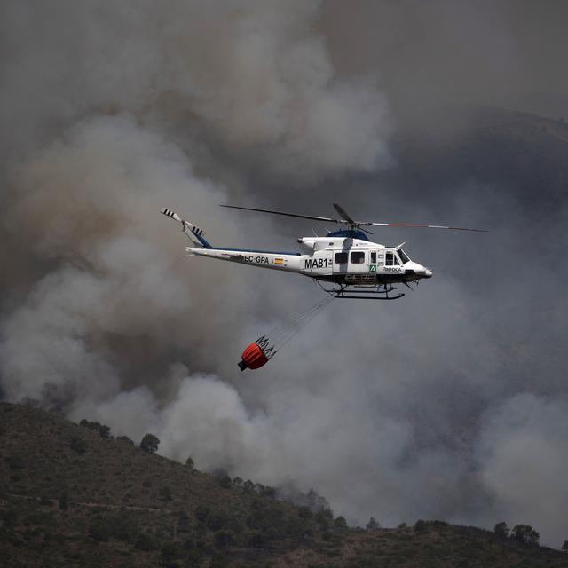 Un hélicoptère tentant de contenir un incendie dans la montagne de la Sierra Bermeja, dans la province de Málaga en Espagne, est photographié depuis Benahavís, le 9 juin 2022. [AFP - Jorge Guerrero]