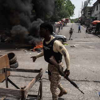 Des policiers ramassent des pneus sur les barricades lors d'une manifestation citoyenne pour dénoncer l'insécurité et les enlèvements constants, à Port-au-Prince, Haïti, le 19 mai 2022. [EPA/KEYSTONE - Johnson Sabin]