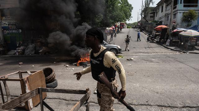 Des policiers ramassent des pneus sur les barricades lors d'une manifestation citoyenne pour dénoncer l'insécurité et les enlèvements constants, à Port-au-Prince, Haïti, le 19 mai 2022. [EPA/KEYSTONE - Johnson Sabin]