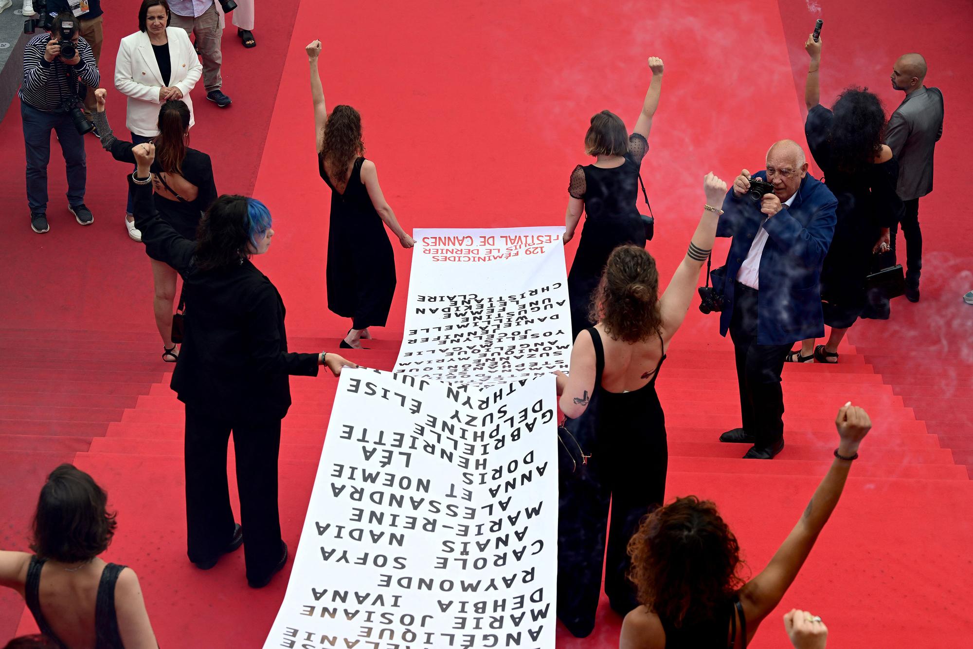 Des membres du groupe féministe "Les Colleuses" ont déroulé une banderole sur le tapis rouge avec le nom des 129 victimes de féminicides en France, "depuis le dernier Festival de Cannes" en juillet 2021. [AFP - Antonin Tuillier]