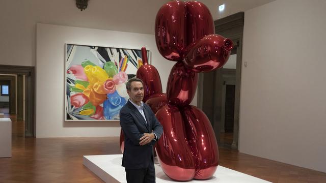 L'artiste Jeff Koons devant son "Balloon dog" lors d'une rétrospective au Palazzo Strozzi à Florence en 2021. [AP Photo/Keystone - Francesco Fedeli]