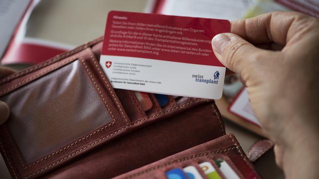 Une femme sort de son porte-monnaie sa carte de don d'organes de Swisstransplant, la Fondation nationale suisse pour le don et la transplantation d'organes, photographiée le 30 avril 2021 à Uster. [KEYSTONE - Christian Beutler]