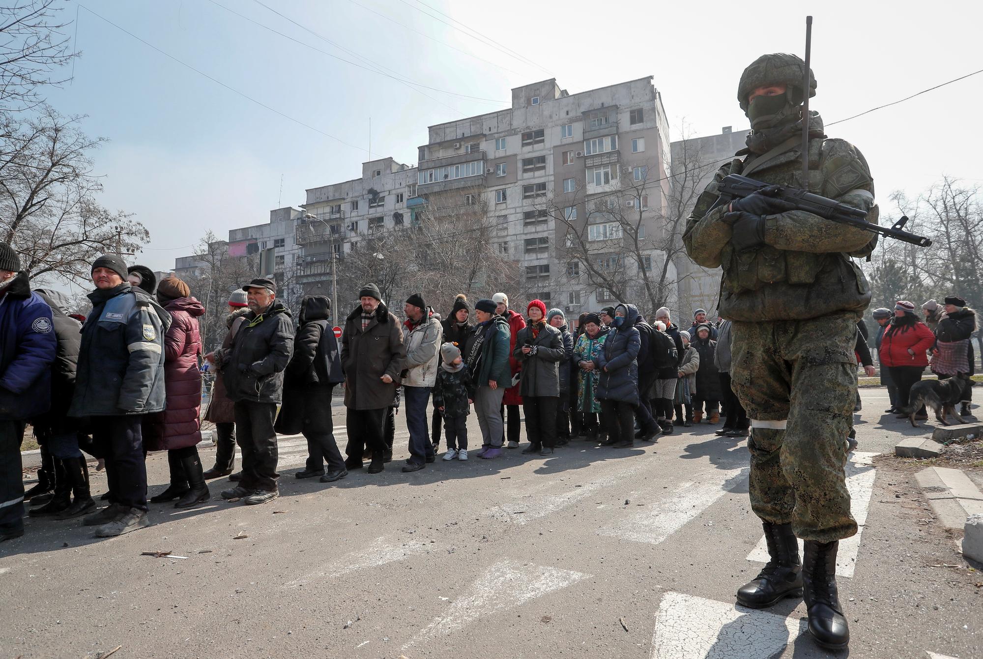 Un soldat russe encadre des résidents de Marioupol. [Reuters - Alexander Ermochenko]