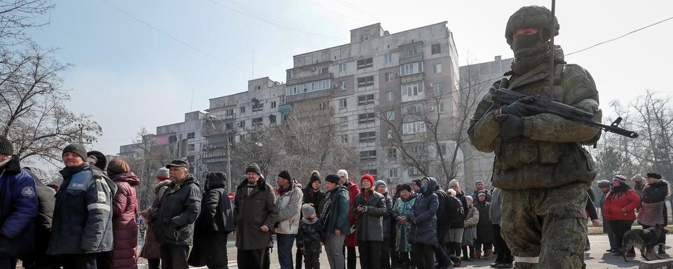 Un soldat russe encadre des résidents de Marioupol. [Reuters - Alexander Ermochenko]