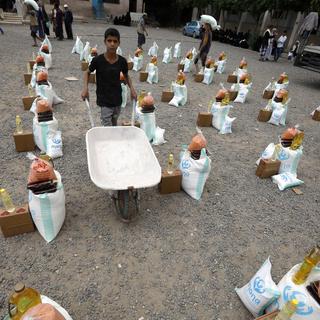Un Yéménite pousse une brouette vide à travers des rations alimentaires d'urgence, fournies par l'agence de secours Mona, pour les personnes touchées par la guerre, à Sana'a, au Yémen, le 24 avril 2022. [EPA/KEYSTONE - Yahya Arhab]