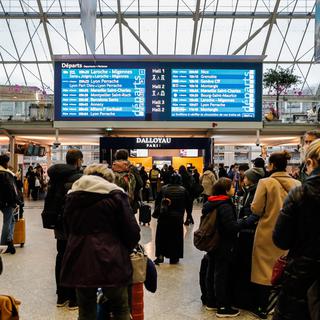 Des voyageurs regardent les informations du tableau de la Gare de Lyon à Paris durant la grève des SNCF. [EPA/Keystone - Teresa Suarez]