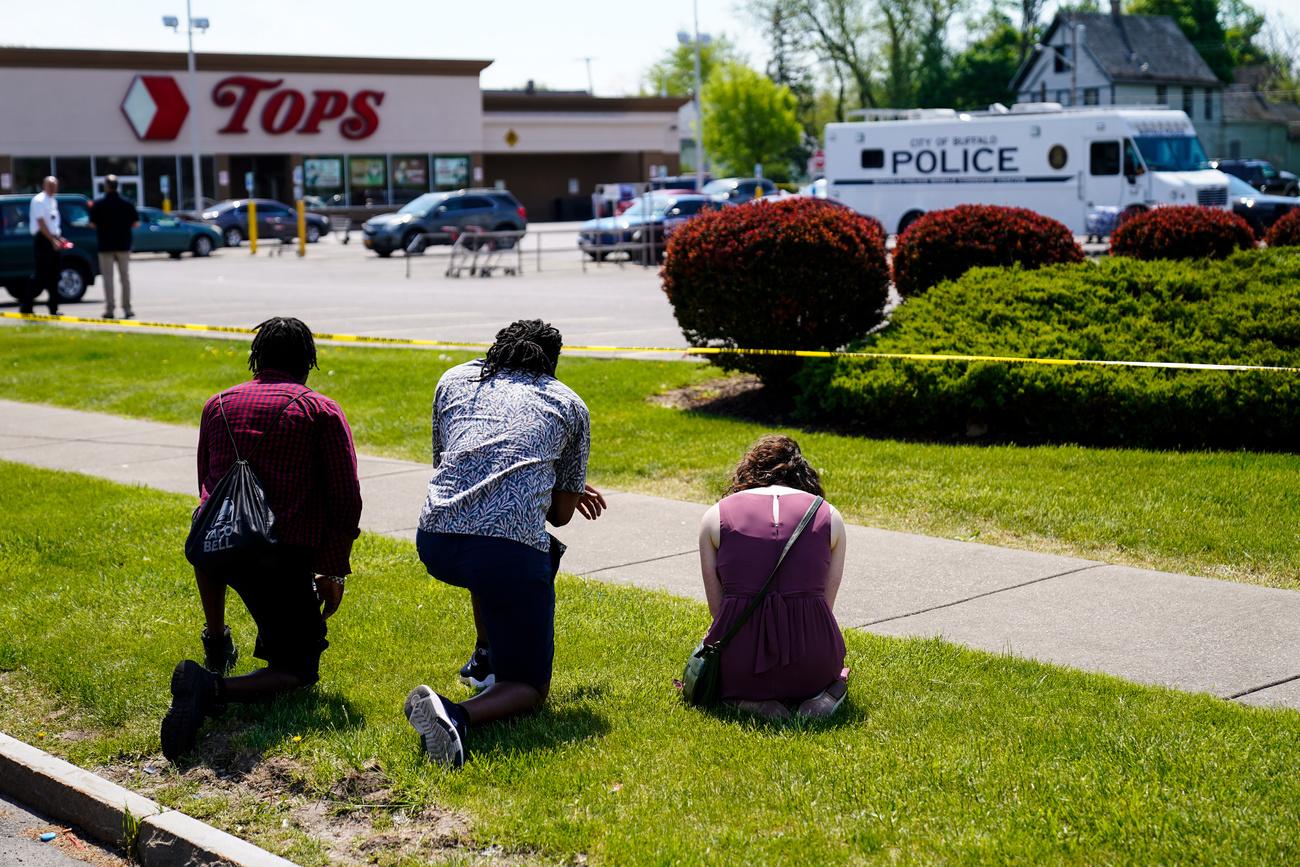 Des gens se recueillent le 15 mai 2022 devant le supermarché Tops de Buffalo où un suprémaciste blanc a tué 10 personnes. [Keystone - AP Photo/Matt Rourke]