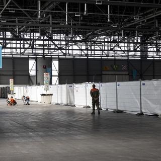 Des enfants réfugiés ukrainiens jouent devant les caisses de l'abri d'urgence pour réfugiés ukrainiens dans la halle 1 de Palexpo, mardi 12 avril 2022 à Genève. [KEYSTONE - Salvatore Di Nolfi]