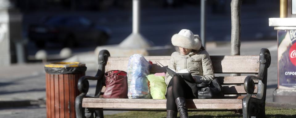 Une femme qui lit sur un banc à Kiev, Ukraine. [EPA/Keystone - Zurab Kurtsikidze]