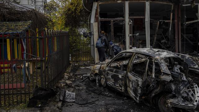 Des habitants inspectent un magasin détruit un jour plus tôt lors d'une attaque russe à Kherson, dans le sud de l'Ukraine, le vendredi 25 novembre 2022. [Keystone - AP Photo/Bernat Armangue]