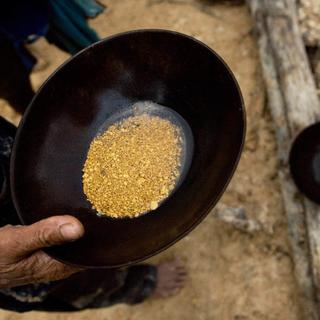 Le mineur Abel, à droite, tient une casserole contenant des pépites d'or après une journée de travail à la mine d'or sauvage Eldorado do Juma, près d'Apui, en Amazonie brésilienne, jeudi 1er février 2007. [AP Photo/KEYSTONE - Victor R. Caivano]
