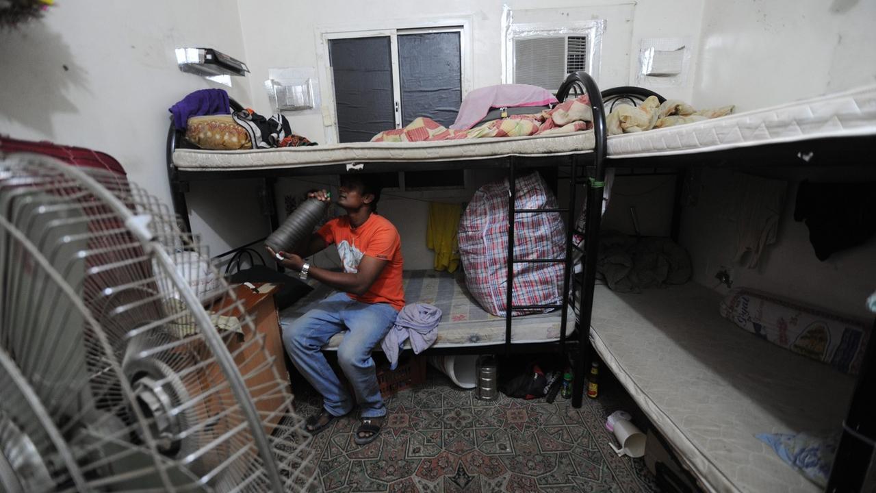 Une photo datée de 2012 montre un travailleur migrant assis sur un lit superposé dans son logement au Qatar [Keystone]