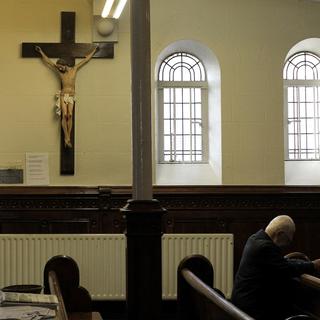 Un homme prie pendant la messe à l'église catholique romaine St Mary à Belfast, en Irlande du Nord. [KEYSTONE - Peter Morrison / AP Photo]