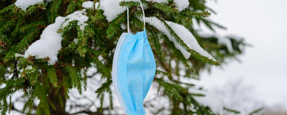 Un masque usagé abandonné dans la neige. [Depositphotos - Tataks]