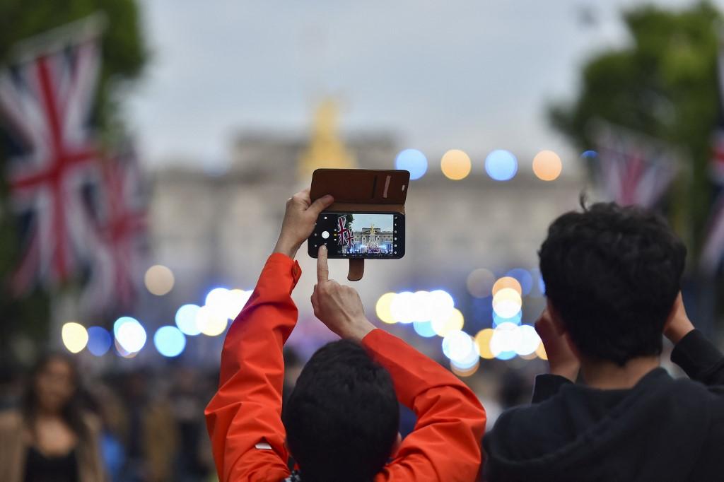 Une personne immortalise les célébrations pour le jubilé de la reine devant le palais de Buckingham, le 3 juin 2022. [AFP - Ivan Yordanov]