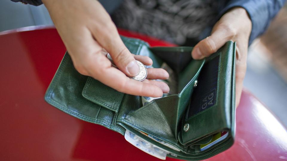 Une femme met de l'argent dans son porte-monnaie. [Keystone - Gatean Bally]