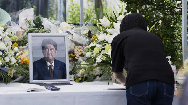 Une femme écrit un message après avoir déposé un bouquet de fleurs pour l'ancien Premier ministre japonais assassiné Shinzo Abe, le 11 juillet 2022 à Tokyo. [KEYSTONE - Hiro Komae / AP Photo]