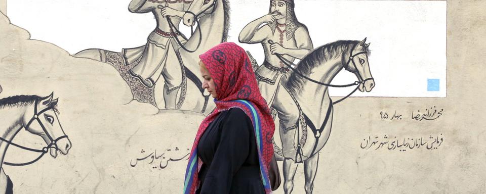 Une femme voilée passe devant une peinture murale à Téhéran le 10 octobre 2022. [EPA - Abedin Taherkenareh]