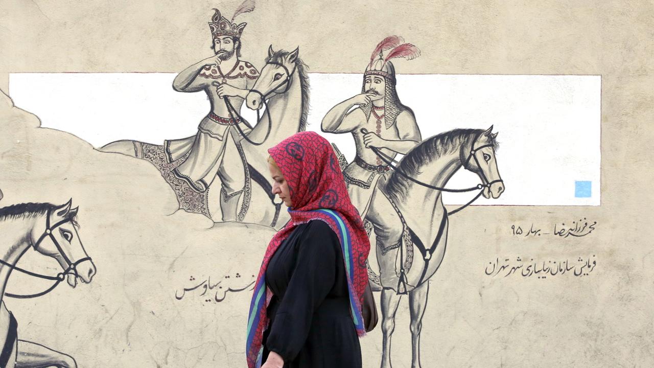 Une femme voilée passe devant une peinture murale à Téhéran le 10 octobre 2022. [EPA - Abedin Taherkenareh]