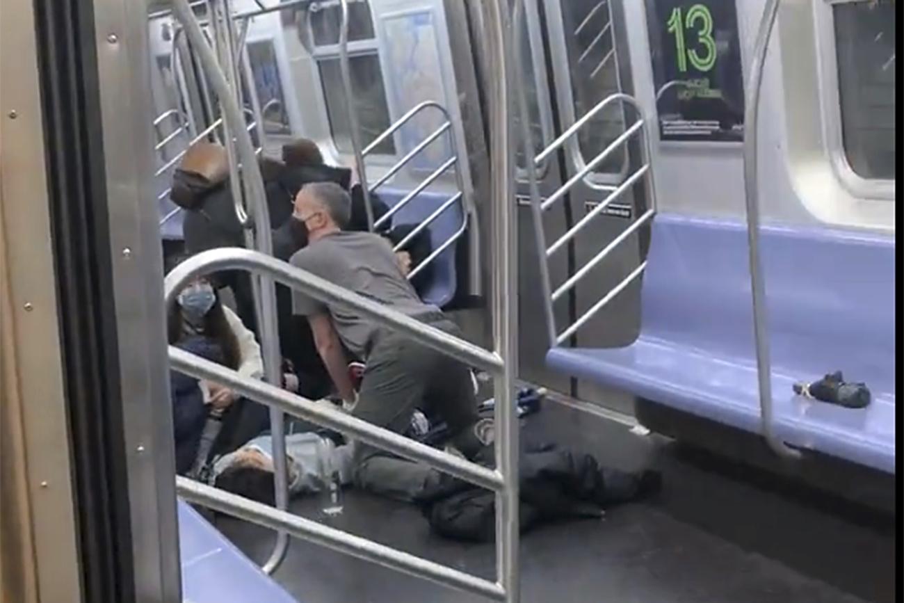 Le tireur a déclenché un engin fumigène dans le métro de New York avant d'ouvrir le feu sur des passagers. Ici, un passager aide un blessé. [Keystone - Will B Wylde]