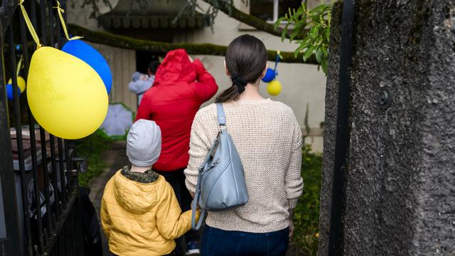 Des membres d'une famille ukrainienne réfugiés en Suisse, à leur arrivée dans une maison mise à disposition à Pully (VD). [Keystone - Jean-Christophe Bott]