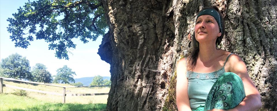 Florence Reber Mittenpergher au pied du plus vieux chêne d’Europe à Châtillon (JU). Photo prise pour son passage dans Les bonnes ondes le 13.07.2022. [RTS - Antoine Droux]