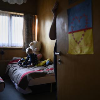 Un enfant ukrainien joue sur son lit au mémorial national pour les enfants placés en institution et en famille d'accueil à Muemliswil. Il est accueilli par la fondation Guido Fluri. Le 11 mars 2022. [Keystone - Anthony Anex]