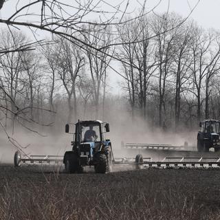 Des fermiers ukrainiens préparent le sol près de Kiev avant de semer des céréales. [Keystone/EPA - Sergey Dolzhenko]