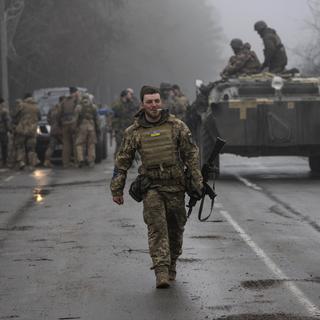 Un soldat de l'armée ukrainienne marche après une opération de ratissage militaire visant à rechercher d'éventuels restes de troupes russes après leur retrait des villages dans la banlieue de Kiev, en Ukraine, vendredi 1er avril 2022. [AP Photo/Keystone - Rodrigo Abd]
