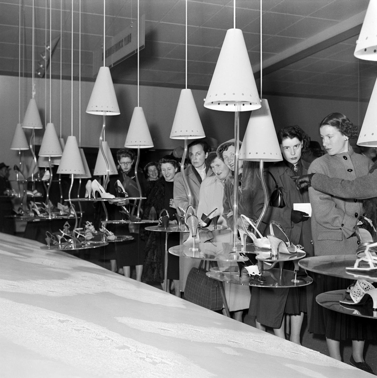 Des visiteuses admirent les chaussures de l'entreprise Bally de Schönenwerd lors de la 37e Foire d'échantillons de Bâle, en avril 1953. [Keystone - KRAFT / KOCH]
