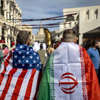 Des fans avec les drapeaux de l'Iran et des USA à Doha le 29.11.22. [Keystone - EPA/Martin Divisek]