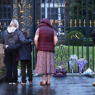 Des personnes déposent des fleurs au château de Hillsborough, en Irlande du Nord, le jeudi 8 septembre 2022, après l'annonce du décès de la reine Elizabeth II. [PA via AP/Keystone - Peter Morrison]