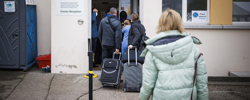 Des personnes en provenance d'Ukraine sont photographiées avec leurs valises au Centre fédéral asile de Boudry (NE). [Keystone - Valentin Flauraud]