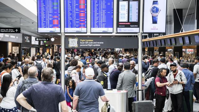 Des passagers photographiés à l'aéroport de Zurich au moment où les vols commencent à reprendre après une panne informatique qui a touché Skyguide. [Keystone - Ennio Leanza]