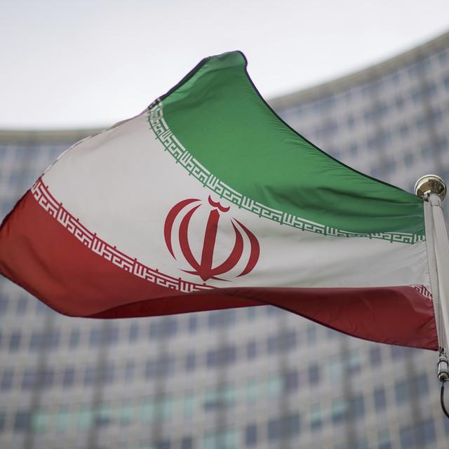 Le drapeau iranien devant le bâtiment de l'Agence internationale de l'énergie atomique. [Keystone - Michael Gruber]