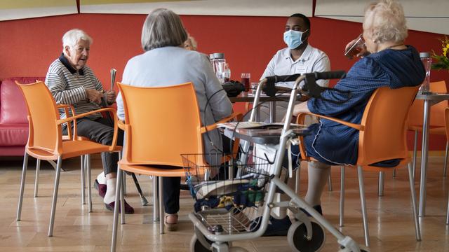 Un soldat des troupes sanitaires de l'armée suisse, deuxième à partir de la droite, discute avec des résidents âgés d'un établissement médico-social, EMS, lors de la pandémie de coronavirus (Covid-19), le mardi 12 mai 2020. [KEYSTONE - Laurent Gillieron]