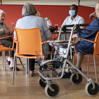 Un soldat des troupes sanitaires de l'armée suisse, deuxième à partir de la droite, discute avec des résidents âgés d'un établissement médico-social, EMS, lors de la pandémie de coronavirus (Covid-19), le mardi 12 mai 2020. [KEYSTONE - Laurent Gillieron]
