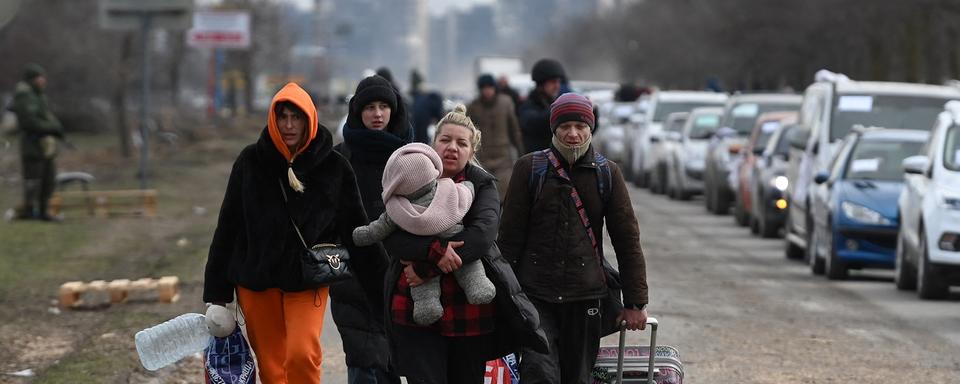 Des personnes marchent le long d'une route, quittant la ville assiégée de Marioupol. [AFP - Maksim Blinov]