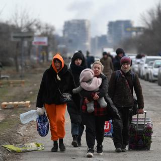 Des personnes marchent le long d'une route, quittant la ville assiégée de Marioupol. [AFP - Maksim Blinov]