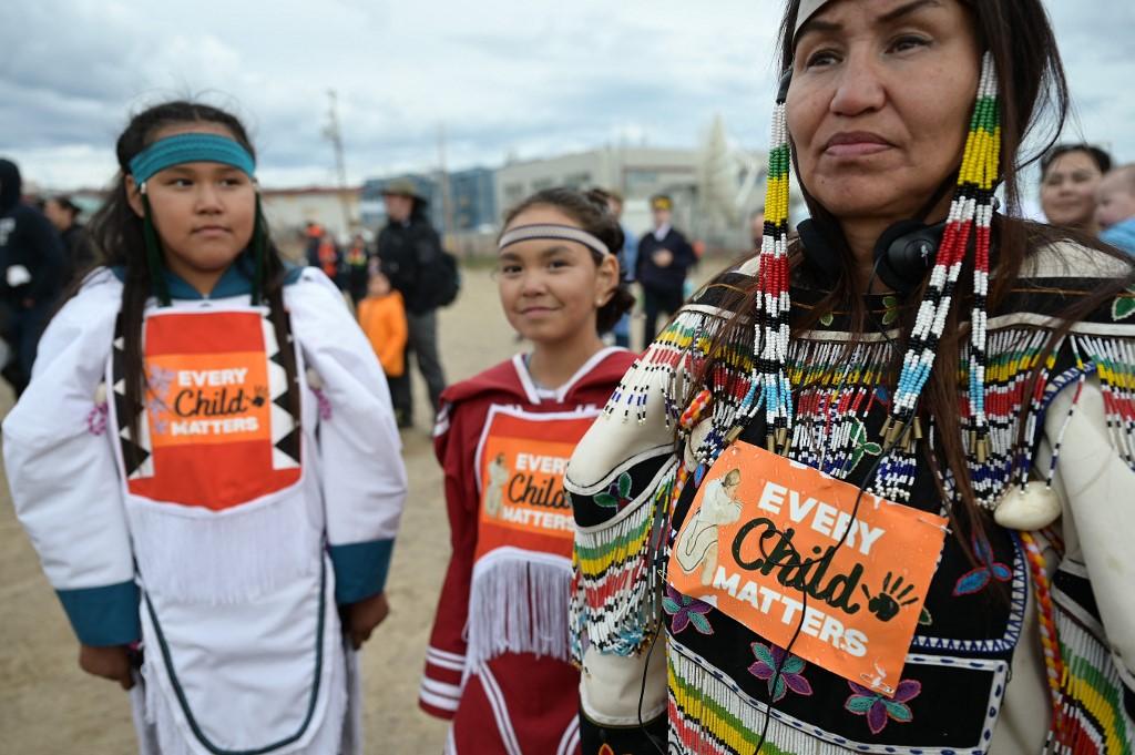 Une femme et des enfants autochtones portent sur leurs vêtements l'inscription "Chaque enfant compte" en attendant l'arrivée du pape François à l'école Nakasuk à Iqaluit, au Nunavut. [AFP - Vincenzo Pinto]