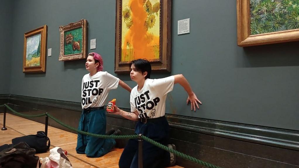 Deux militantes du mouvement "Just Stop Oil" ont collé leurs mains sous le tableau de Van Gogh "Tournesols" à la National Gallery de Londres le 14 octobre 2022. [AFP - Just Stop Oil]