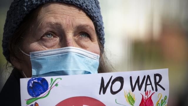 Une femme porte une pancarte "non à la guerre" lors d'une manifestation à Porto, le 20 février. [Keystone - José Coelho]