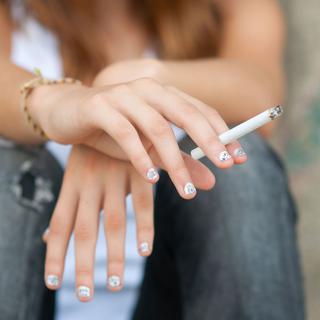 Gros plan sur la main d'une adolescente tenant une cigarette. [Depositphotos - SolidPhotos]