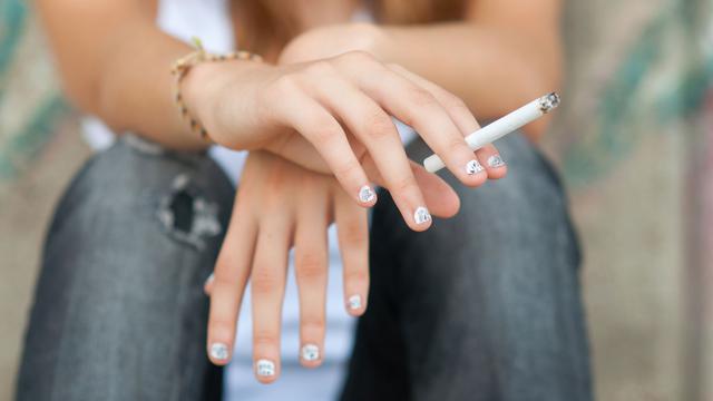 Gros plan sur la main d'une adolescente tenant une cigarette. [Depositphotos - SolidPhotos]