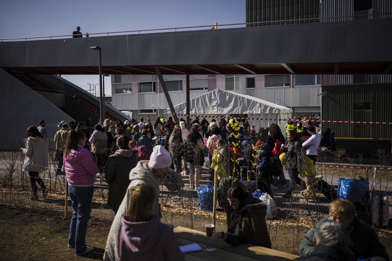Des réfugiés ukrainiens font la queue et attendent d'être enregistrés devant le centre fédéral d'asile de Zurich, le 13 mars 2022. [KEYSTONE - Michael Buholzer]