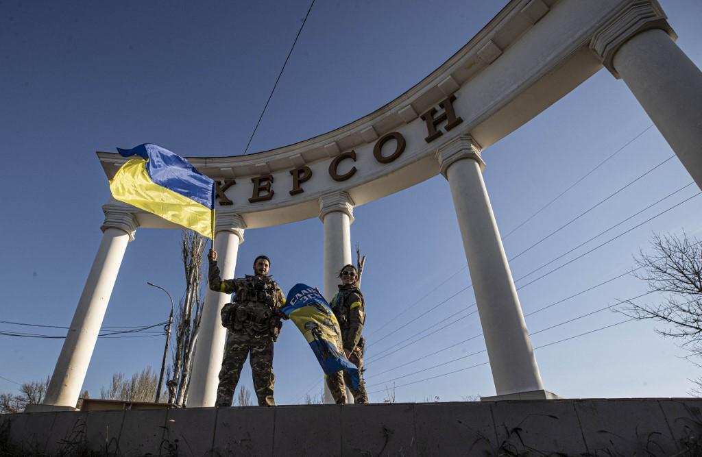 Des soldats ukrainiens devant le panneau d'entrée de la ville de Kherson. [afp - Metin Aktas / Anadolu Agency]