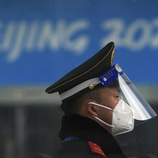 Un policier paramilitaire chinois portant un masque et un écran facial pour se protéger du coronavirus monte la garde à l'entrée d'un centre de presse principal (MPC) barricadé pour les Jeux olympiques d'hiver à Pékin, mercredi 19 janvier 2022. [AP Photo/KEYSTONE - Andy Wong]